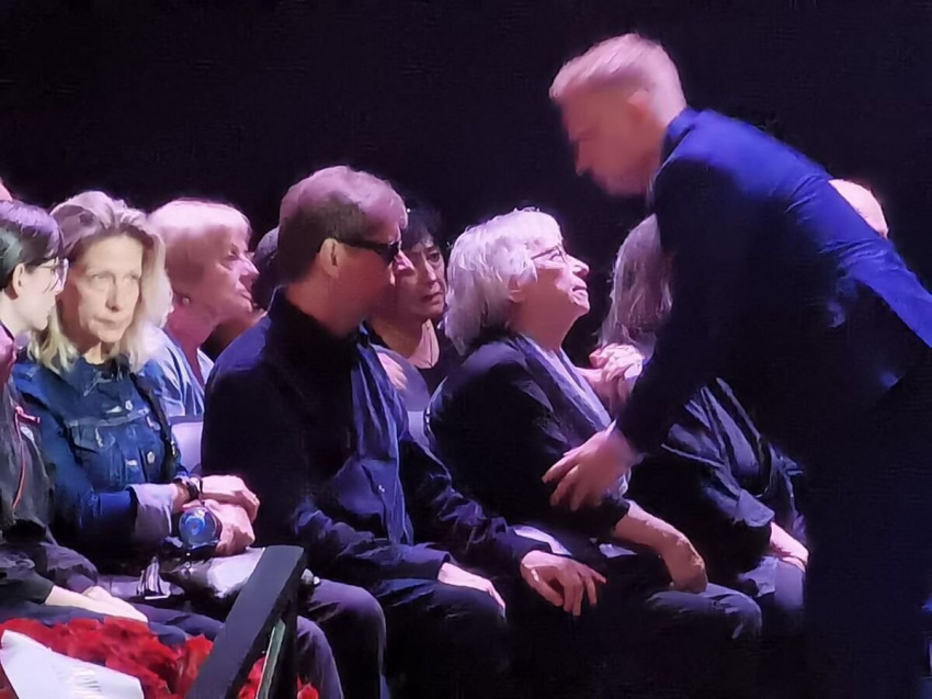 Гроб Игоря Ясуловича усыпан цветами, а рядом сидит убитая горем жена